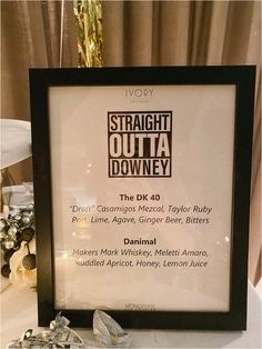 there is a framed sign that says straight outa downey on the table with other items