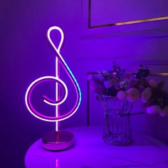 a purple light that is on top of a table next to a vase with flowers