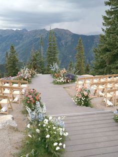 an outdoor ceremony set up with wooden chairs and flowers on the aisle, overlooking mountains