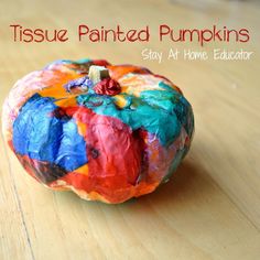 a colorful painted pumpkin sitting on top of a wooden table with the words tissue painted pumpkins