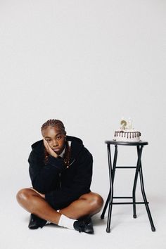 a woman sitting on the ground next to a table