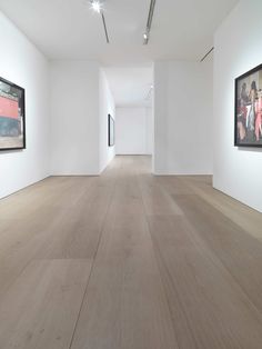 an empty room with paintings on the wall and wooden flooring in front of it