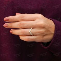 a woman's hand wearing a ring with pearls on the middle of her finger