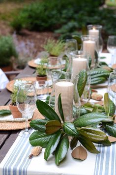 an image of a table setting with candles and greenery on the table for dinner