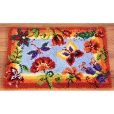 a colorful rug with flowers and butterflies on the floor in front of a wooden floor