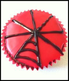 a red cupcake with chocolate icing in the shape of a umbrella on top