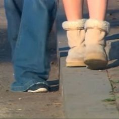 two people standing next to each other with their feet in the air on a sidewalk