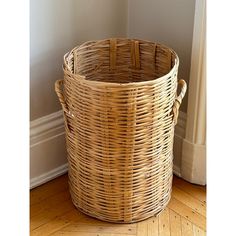 a large wicker basket sitting on top of a hard wood floor next to a wall