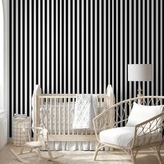 a baby's room with black and white striped wallpaper, rocking chair, crib and lamp