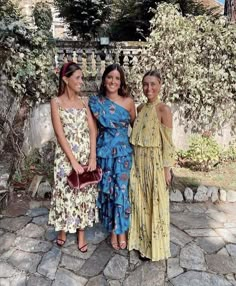 three women standing next to each other in dresses