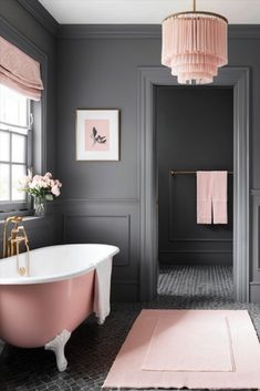 a pink bath tub sitting in a bathroom next to a white toilet and sink under a pink chandelier