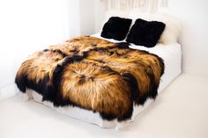 a bed with two pillows on top of it and a fur blanket over the headboard