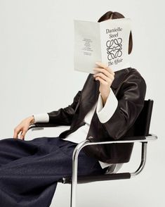 a woman sitting in a chair reading a book with her head covered by a paper