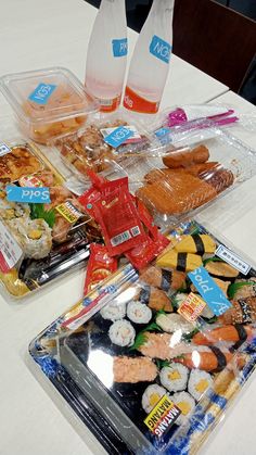 three plastic containers filled with different types of sushi and other food items on a table