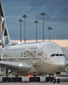 an airplane that is sitting on the tarmac at dusk with clouds in the background