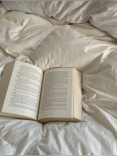 an open book sitting on top of a bed