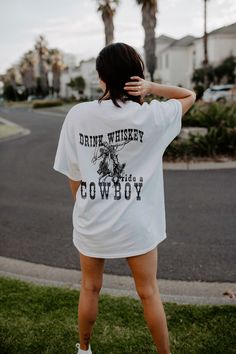 "This is hands down the comfiest DRINK WHISKEY RIDE A COWBOY tee you will wear this season! I am absolutely obsessed with this shirt and I am sure YOU will love it too ! Rock your Desert Trip with this tee ! This cute minimal design looks so good on any colour !  * Q U I C K F A C T S * This design is a unique, one-of-a-kind awesome illustration that has been created in house. ✺ 100% Cotton (fiber content may vary for different colors) ✺ Classic fit ✺ Sizing is unisex so runs like men's, though Western Shirt Women, Ride A Cowboy, Desert Trip, Digital Printing Machine, Western Graphic Tees, Oversized T Shirt Dress, Cowboy Shirt, Whiskey Drinks, Retro Western