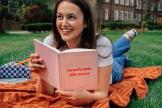 a woman laying on the grass reading a book