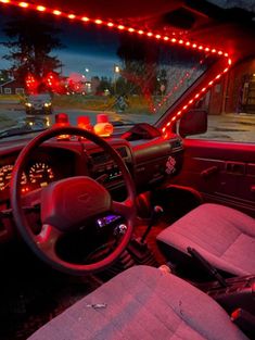 the interior of a vehicle with its lights on and steering wheel illuminated by red leds