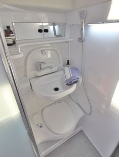 a bathroom with a sink, toilet and shower head mounted to the side of the wall