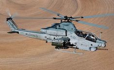 a helicopter flying over a dirt field in the air with propellers on it's wings