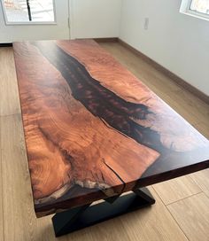 a wooden table sitting on top of a hard wood floor next to an open window