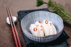 some food in a bowl with chopsticks on the table next to it,