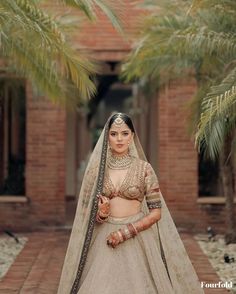 a woman in a bridal outfit standing on a brick walkway with palm trees behind her