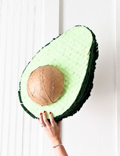 a person holding an avocado shaped cake on top of a white door frame