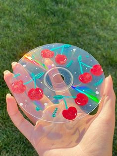 a person holding up a plastic disc with cherries on it in the grass,