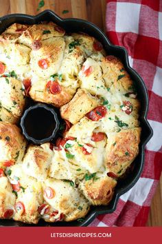 a pan filled with bread covered in cheese and toppings on top of a red checkered table cloth