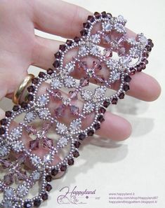 a woman's hand is holding a pink and white brooch with diamonds on it