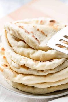 a stack of pita bread on a plate with a spatula in the middle