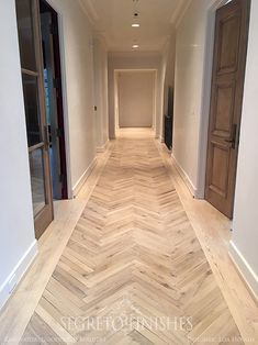 an empty hallway with wooden floors and doors