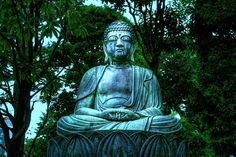 a buddha statue sitting in the middle of a park