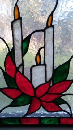 a stained glass window with three candles and a poinsettia flower on it