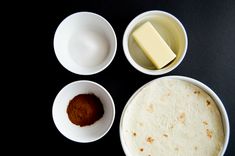 three bowls with different ingredients in them on a black surface, one containing flour and the other containing butter