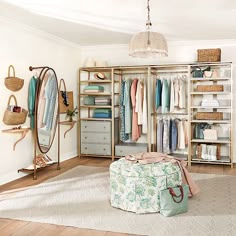 an organized closet with clothes hanging on the walls, and a round ottoman in front of it