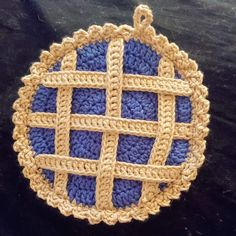 a blue and yellow crocheted dishcloth on a black surface with a hook