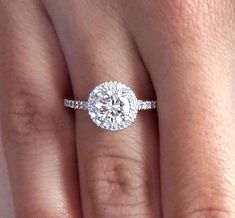 a woman's hand with a diamond ring on top of her finger and the engagement band