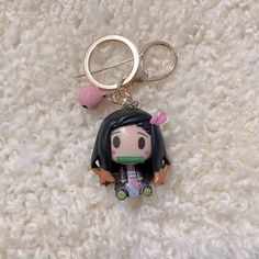 a keychain with a cartoon character on it sitting on a white carpet next to a pair of scissors