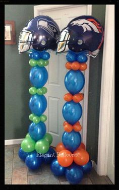 two football helmets sitting on top of each other in front of a door with balloons