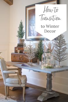 a white table topped with christmas trees under a framed art piece next to a chair