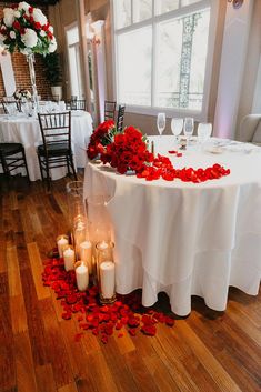 a table with candles and flowers on it in the middle of a room filled with tables