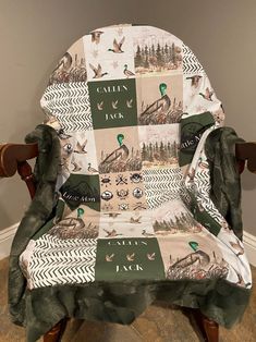 a chair covered in a blanket with ducks and trees printed on the seat cover, sitting against a wall