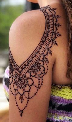 the back of a woman's shoulder with an intricate tattoo design on her arm