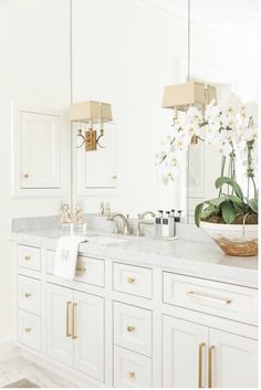 a bathroom with white cabinets and marble counter tops is shown in this image, there are flowers on the vanity