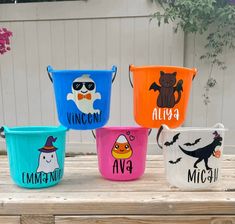 four buckets with different designs on them sitting on a wooden table in front of a fence