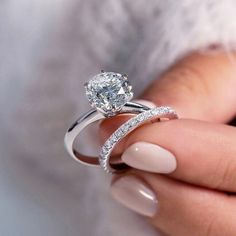 a woman's hand holding an engagement ring with diamonds on the band and side stones