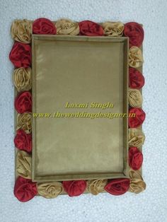 a decorative mirror with red and gold flowers on it's sides, sitting on a white surface